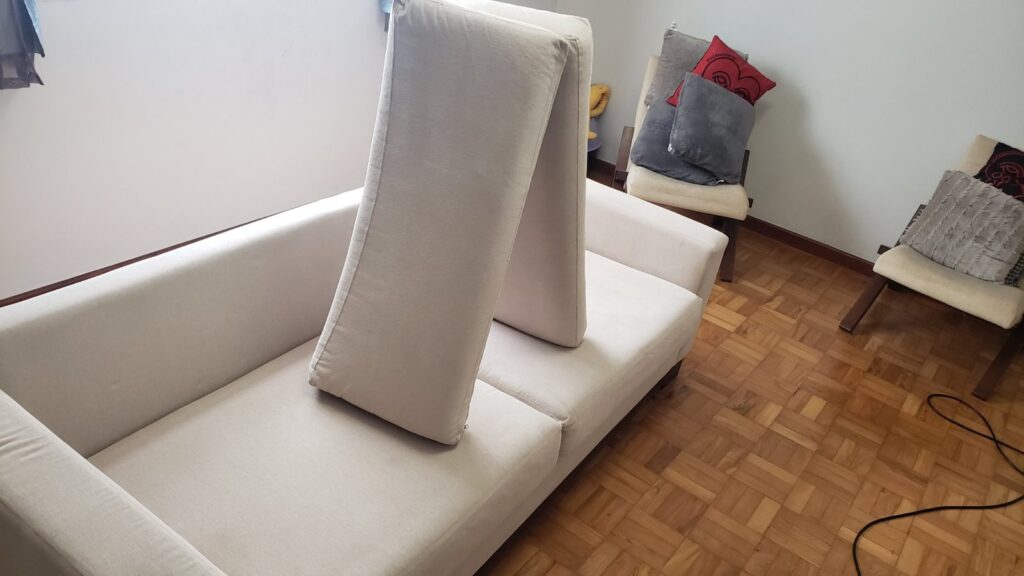 Sofá de 2 lugares bege limpo depois da higienização, com as almofadas em pé para secar